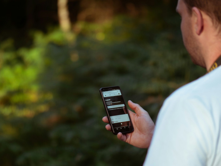 Ein Mann hält ein Smartphone in der Hand und schaut darauf.