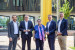 Eine Gruppe von fünf Personen steht im Freien vor einem modernen Gebäude, sie lächeln in die Kamera.