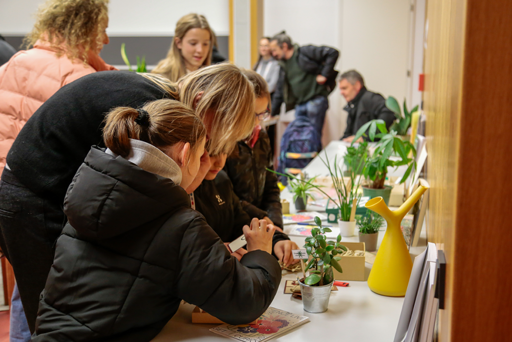 Gruppe von Kindern und Erwachsenen bei praktischer Pflanzenaktivität an Tisch mit kleinen Topfpflanzen