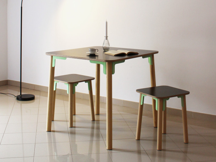 Quadratischer Tisch mit zwei quadratischen Hockern aus Holz. Alle drei Möbelstücken werden mit je 8 Verbindungsstücken an ihrer Unterseite und den Tisch- und Stuhlbeinen zusammengehalten.