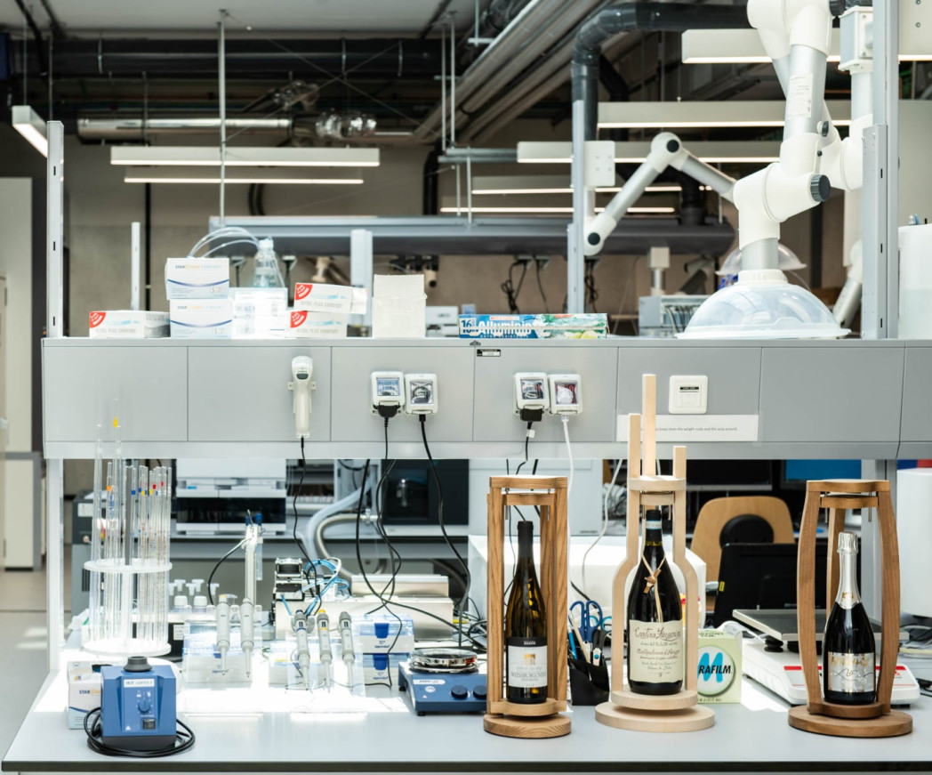 Su un tavolo da laboratorio ci sono tre bottiglie di vino.