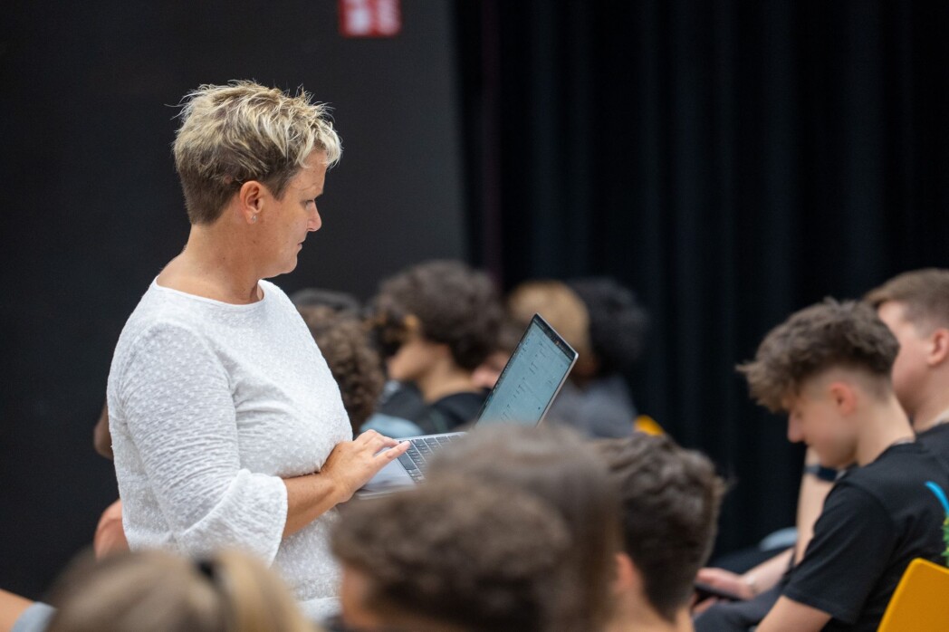Docente con laptop davanti a studenti seduti in aula.