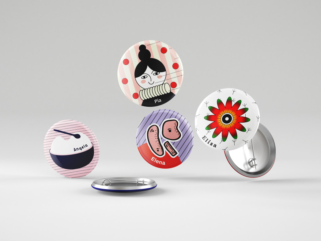 Mehrere runde Buttons mit farbigen Illustrationen und Namen schweben vor grauem Hintergrund; einige zeigen die Rückseite mit Sicherheitsnadel.