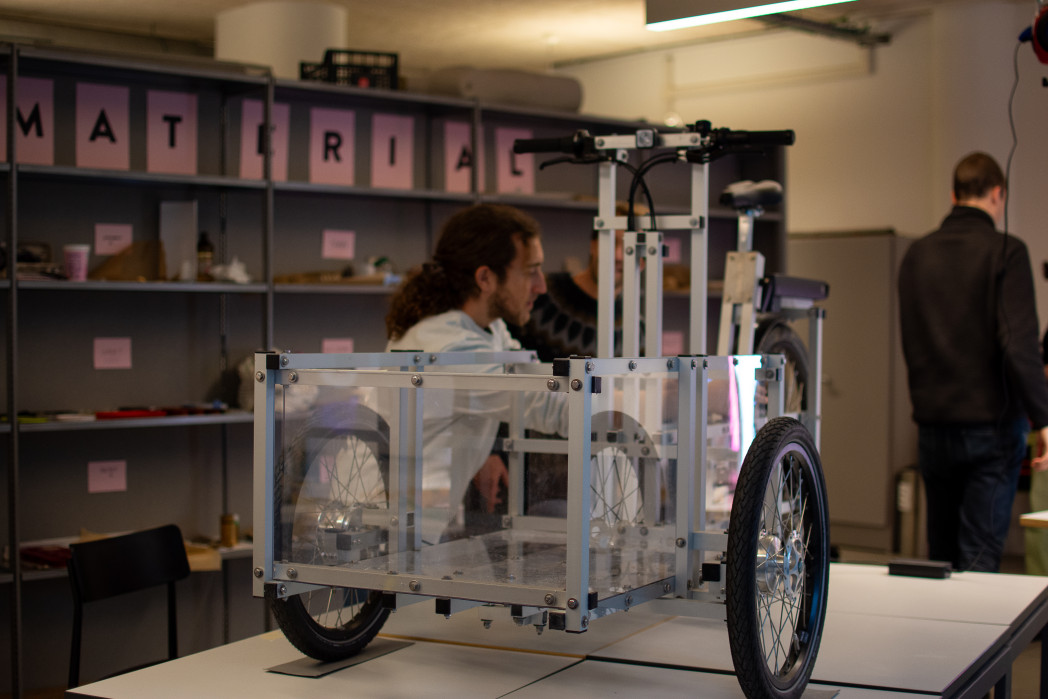 Lastenrad steht auf einem Tisch, Mann werkelt daran