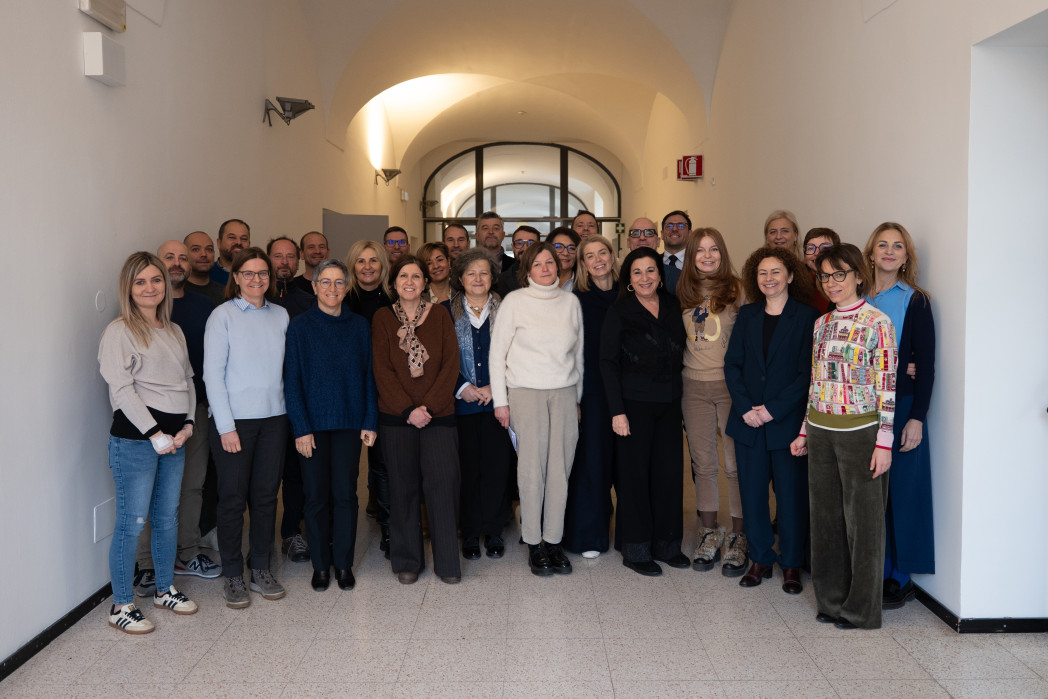 Gruppenfoto von etwa 30 Erwachsenen, die nebeneinander in einem hellen Flur stehen und in die Kamera lächeln.