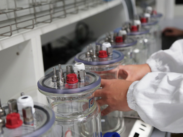 Hände greifen nach Behältern in einem Labor.