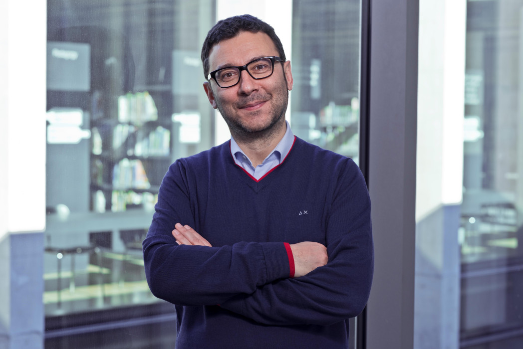 Bild einer Person, die die Publikation in Händen hält. Die Person steht von Bücherregalen.