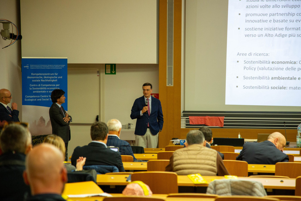 Intervento in un’aula universitaria: una persona parla al pubblico con un microfono, mentre altre persone sono in piedi accanto