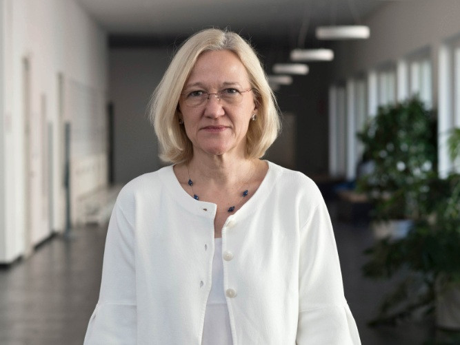 Eine Frau mit weißer Bluse steht auf einem Gang.