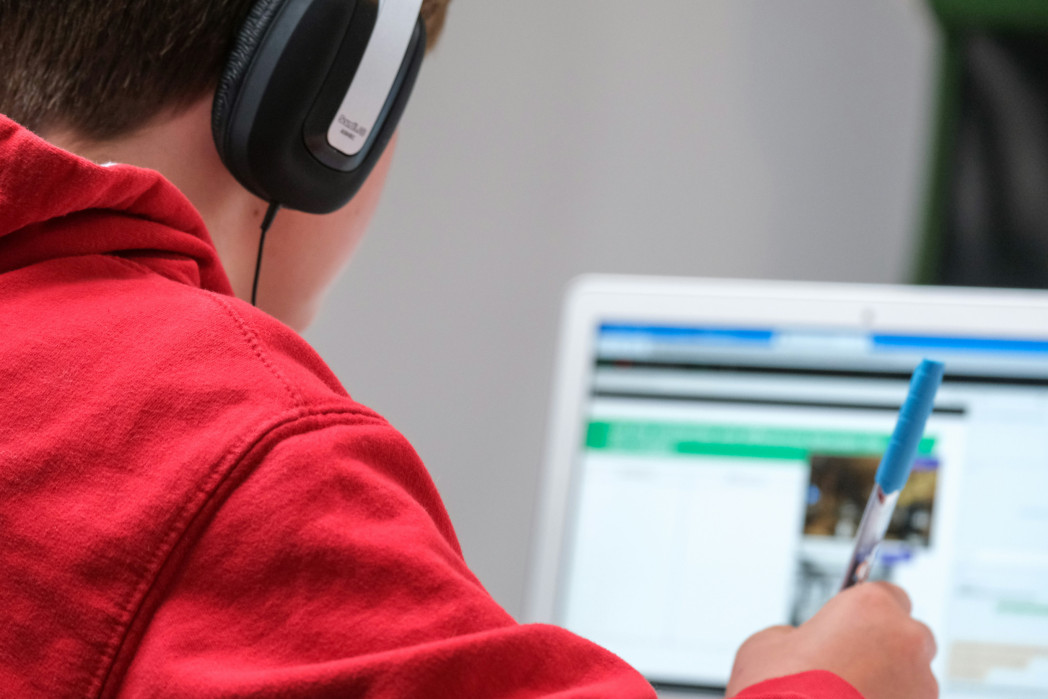 Bambino seduto, con le cuffie, davanti al computer