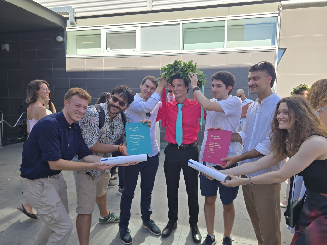 Alessandro Pippa festeggia con amici mostrando le due tesi di laurea.