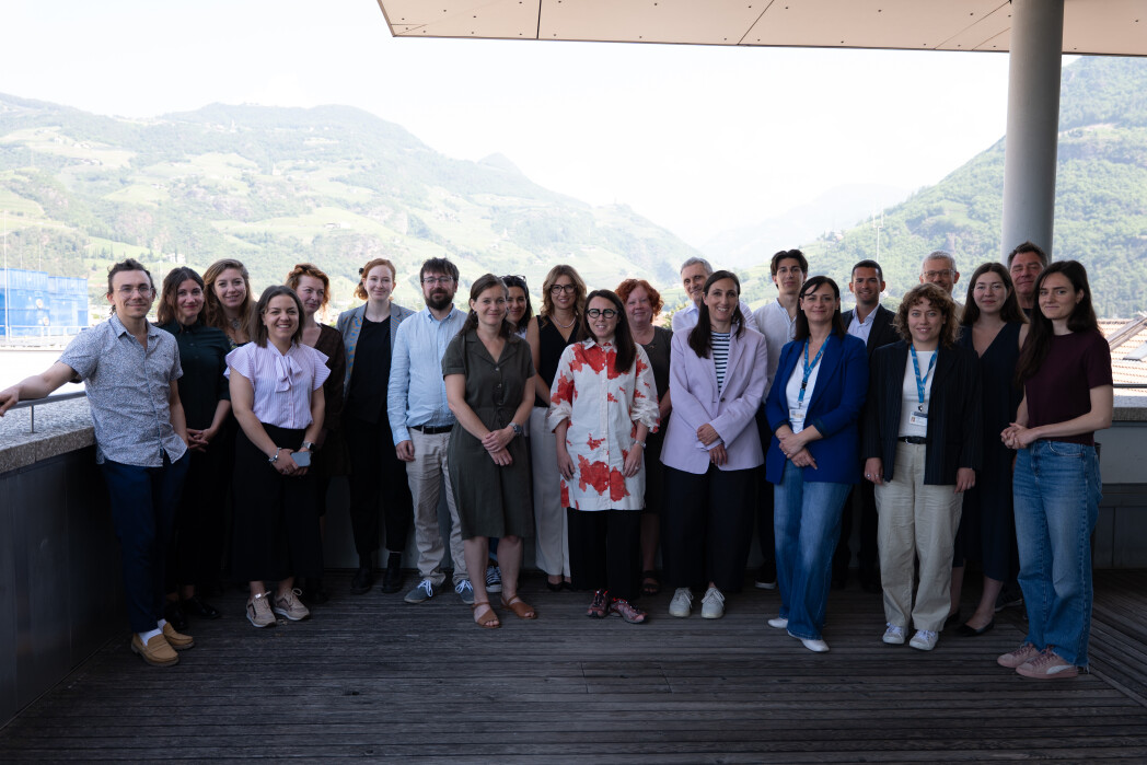 Group of people on a terrace with a mountain landscape in the background.