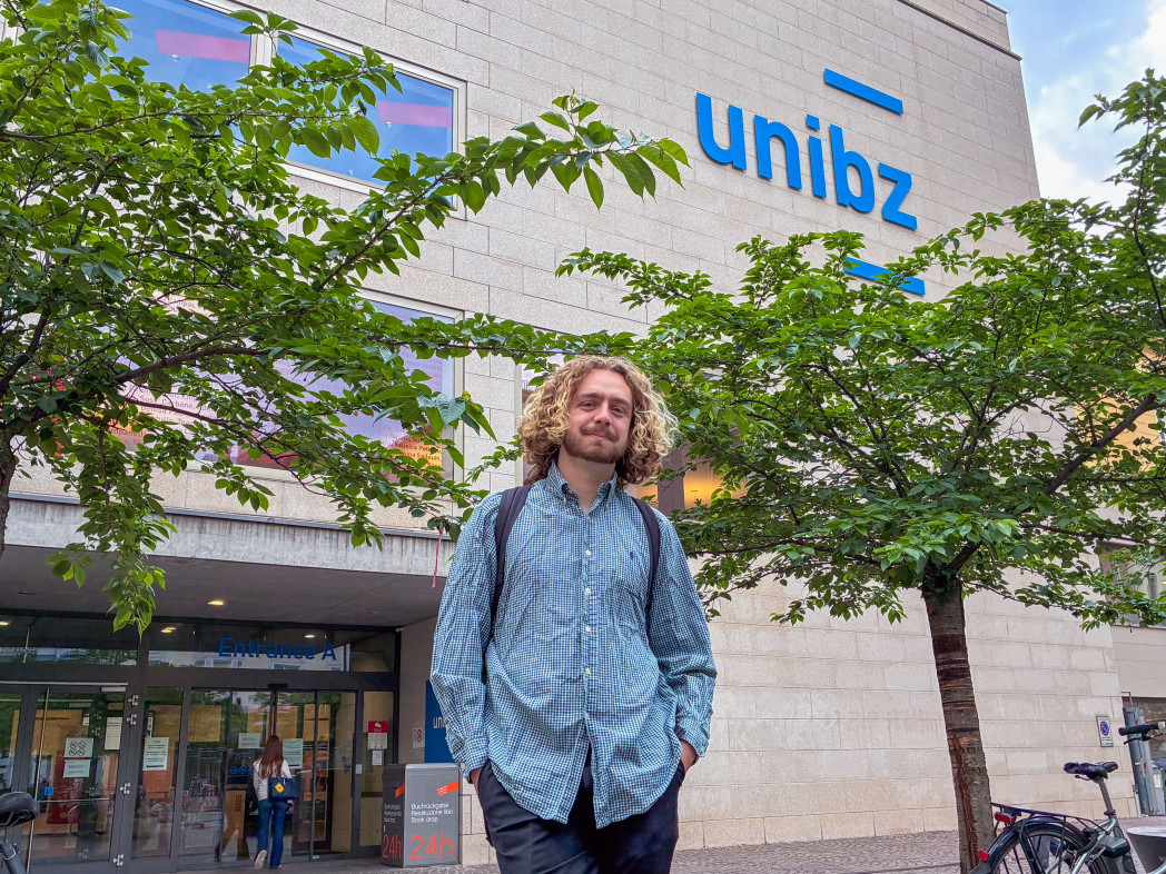 Young male student in front of the university entrance.