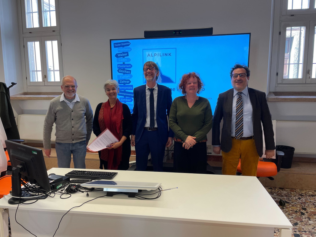 Cinque persone stanno in piedi in un'aula.